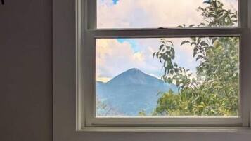 Une chambre à coucher avec un lit, des oreillers et une fenêtre donnant sur la montagne.