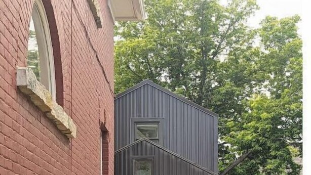 En moderne bygning med to etager, mørkt ydre og et enkelt vindue på øverste etage.