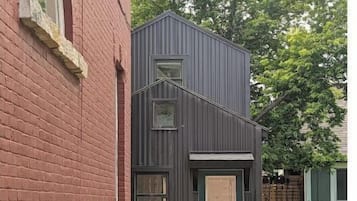 Un bâtiment moderne à deux étages, doté d’une façade sombre et d’une seule fenêtre visible à l’étage supérieur.