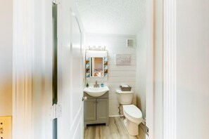 A compact bathroom with a white sink, vanity, and toilet. - Horizon South (Panama City Beach)
