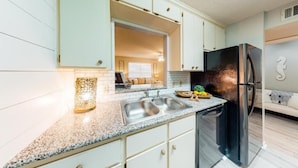 Une cuisine moderne dotée de plans de travail en granit, d’appareils électroménagers en acier inoxydable et de meubles de couleur claire.
