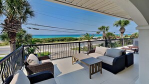 Ein Balkon mit Korbmöbeln, einem kleinen Tisch und Blick auf das Meer.