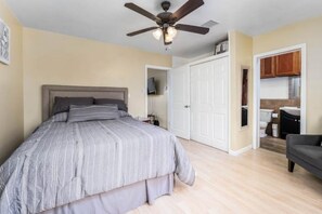 Cozy retreat with a large bed, ceiling fan, and kitchenette.