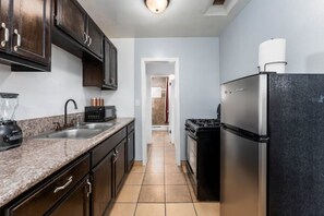 Kitchen features a refrigerator, stove, coffee maker, and blender.