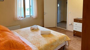 Una habitación de hotel con una cama, un aparador de madera y una puerta que da a otra estancia.