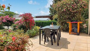An outdoor patio with a table and chairs, surrounded by lush greenery and flowering plants. - Beach front home in Clohars-Carnoët with WiFi (Clohars-Carnoët)