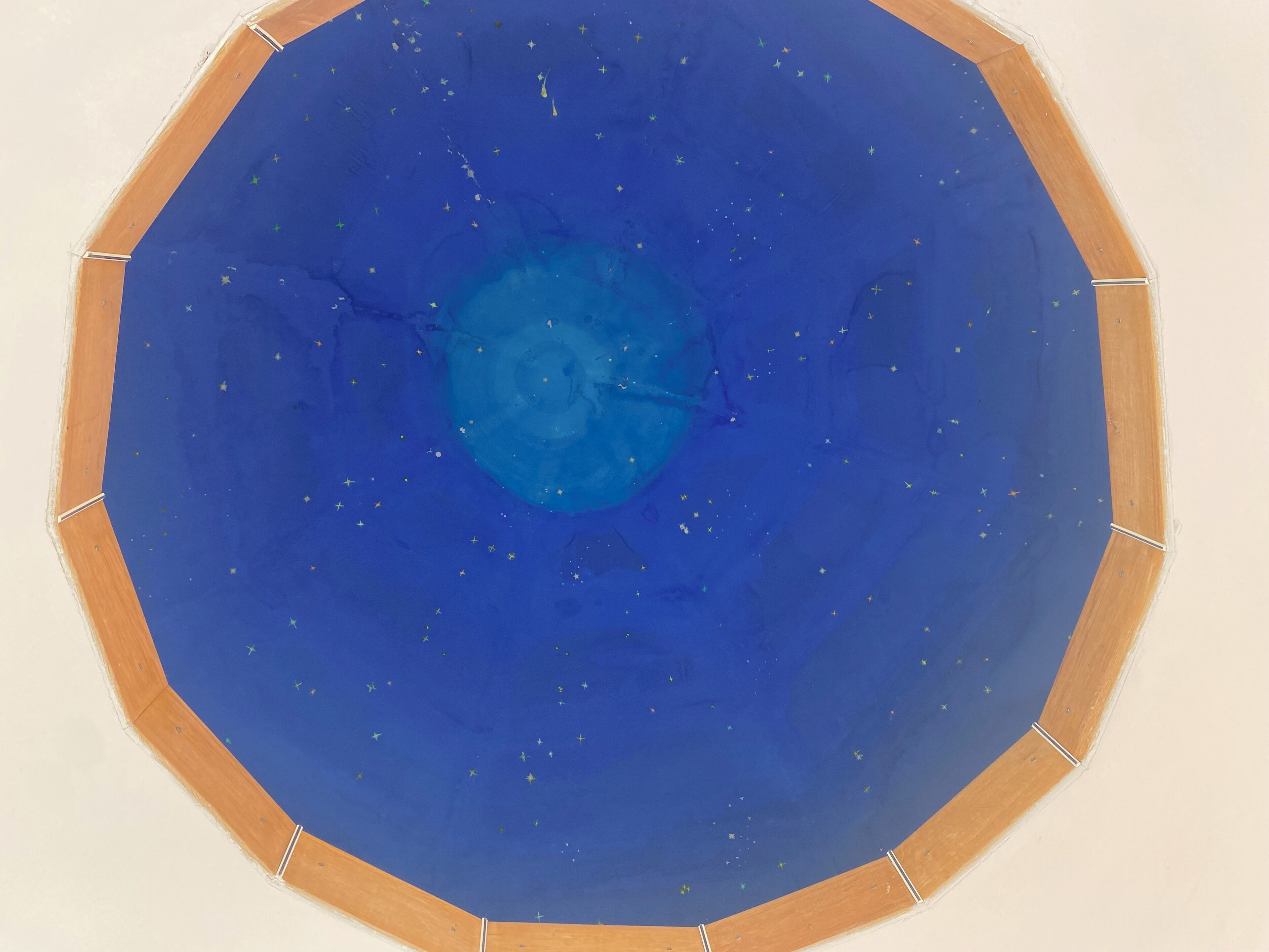 A circular room with a blue starry ceiling and wooden trim.