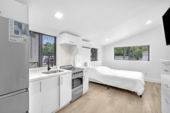 Enjoy a compact room with a kitchenette, single bed, and large windows offering views of the surrounding area.