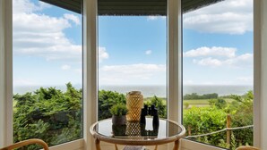 A balcony with a glass table, two chairs, and a view of the ocean. - 2 bedroom cozy home in Nyborg (Nyborg)