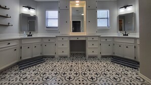 Casa de banho com lavatório duplo, duas espelhas e chão com padrão.