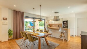 Una cucina moderna con isola centrale, pavimento in legno e illuminazione a sospensione.