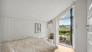 Een slaapkamer met een bed, een raam en een deur.