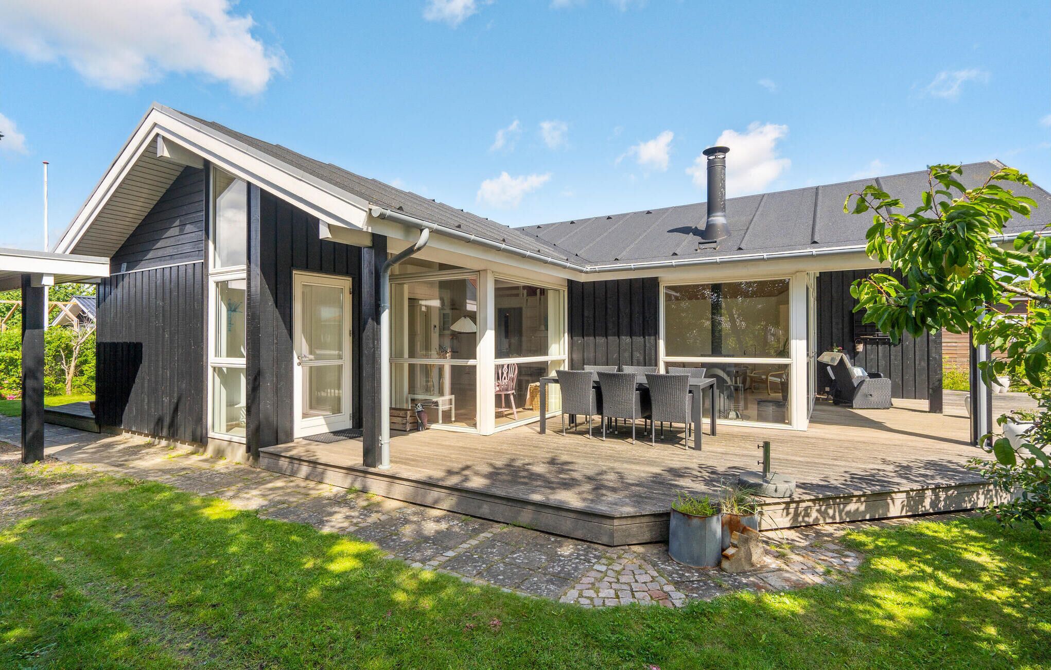 Une maison moderne dotée d’un patio couvert, de grandes fenêtres et d’une cheminée.