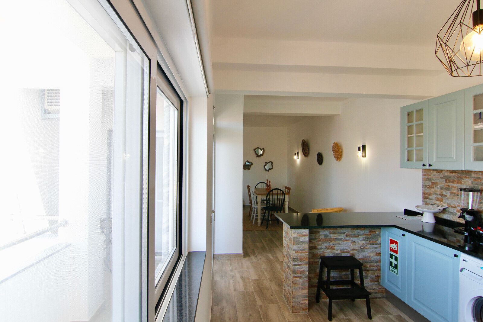 Una cocina moderna con una isla de piedra, armarios azul claro y un comedor con sillas y una mesa.