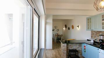 Una cocina moderna con una isla de piedra, armarios azul claro y un comedor con sillas y una mesa.