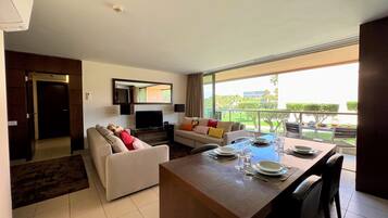 Una sala de estar moderna con comedor, televisor y balcón con vistas al exterior.