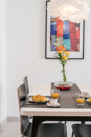 Ein Esstisch mit einem Laptop, einem Croissant und Gläsern Orangensaft.