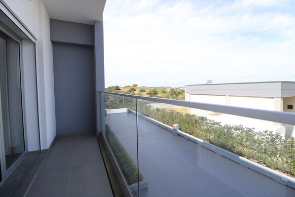 A balcony with a clear view of a landscaped area and distant buildings.