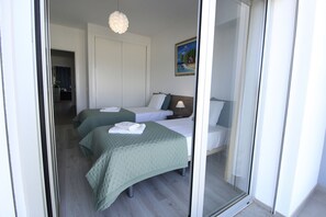 Ein Hotelzimmer mit zwei Betten, einem Bild an der Wand und einer Tür zu einem anderen Raum.