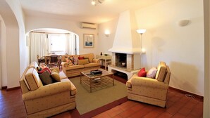 A cozy living room with a sofa set, a coffee table, and a fireplace. - Vilamoura Concept Villa With Pool (Loulé)