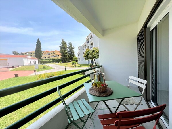 A balcony with a table, chairs, and a view of a building complex.