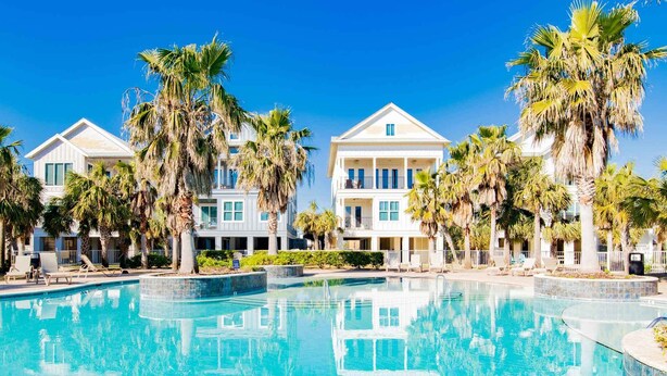 A resort with a large pool, palm trees, and multi-story buildings.
