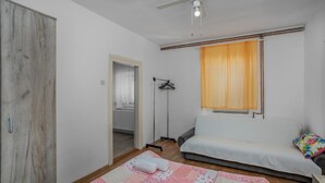 Une petite chambre à coucher, chaleureuse et accueillante, avec un lit simple, une lampe sur pied, un radiateur et une fenêtre avec des rideaux.