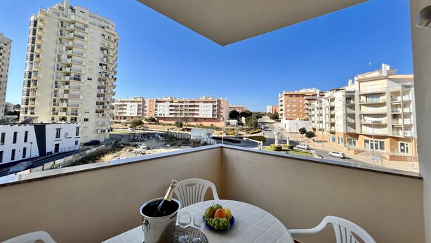 A balcony with a table, a bottle of champagne, and a bowl of fruit. - Armação Pêra Typical by Homing (Silves)