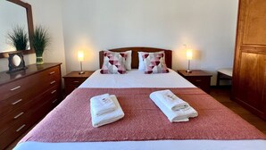 A hotel room with a large bed, two bedside tables with lamps, a wooden dresser, and a mirror on the wall. - Armação Pêra Typical by Homing (Silves)