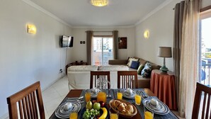 A dining area with a table set for breakfast, including plates, glasses, and a fruit basket. - Armação Pêra Typical by Homing (Silves)