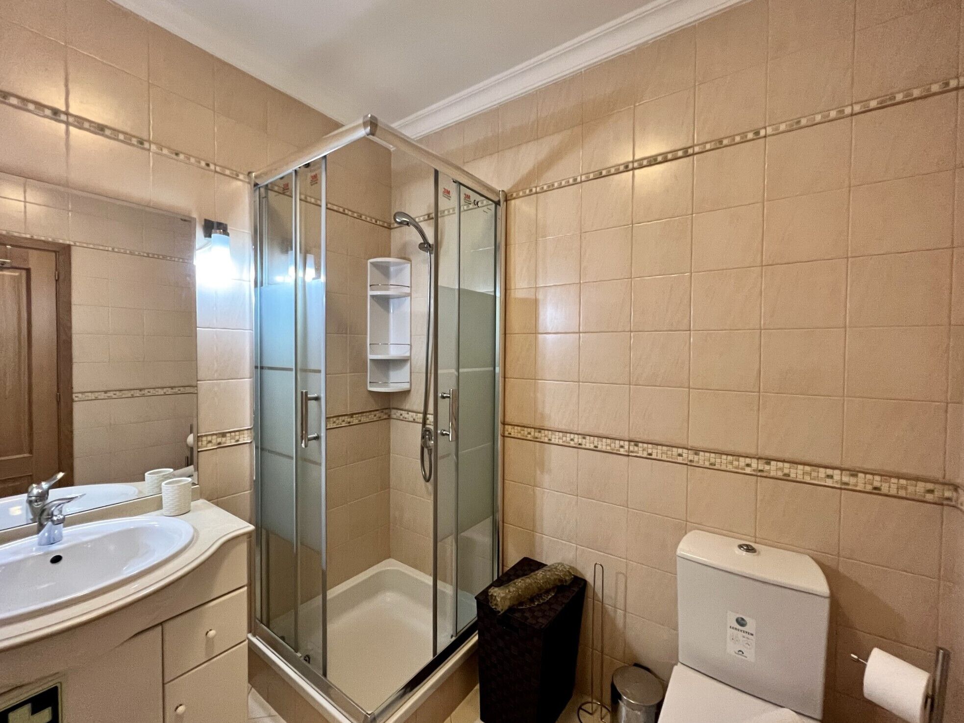 A bathroom with a glass-enclosed shower, a sink, and a toilet.