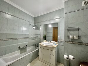 A bathroom with a bathtub, a sink, and a shower. - Armação Pêra Typical by Homing (Silves)