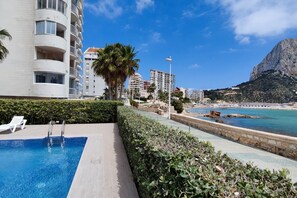 Una piscina con vistas a la ciudad costera, incluyendo un acantilado destacado y una playa.