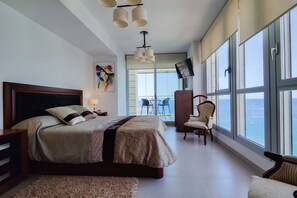 Un dormitorio moderno con una cama grande, televisión y vista al océano.