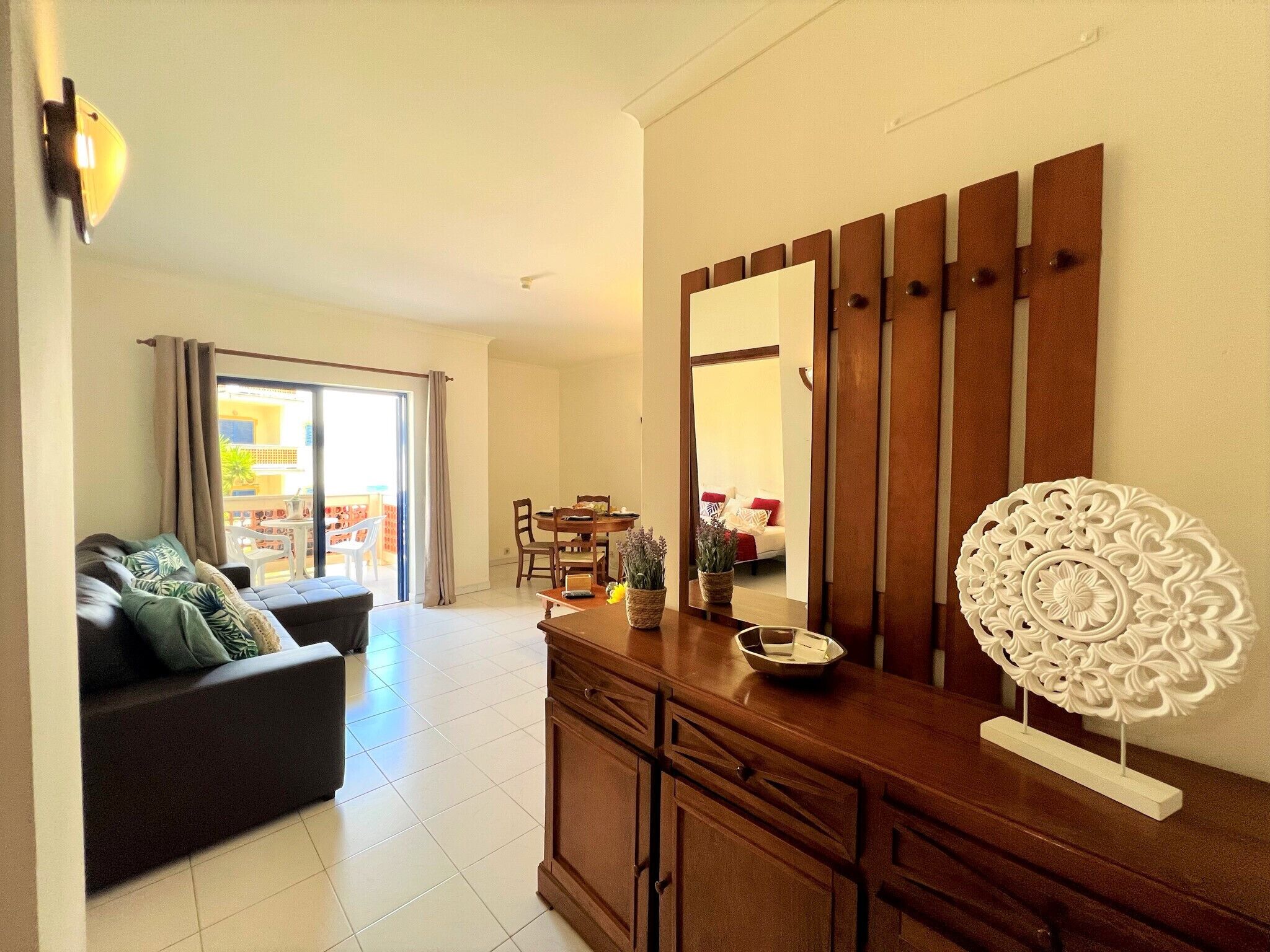 A modern living room with a sofa, a dining table, and a large mirror.