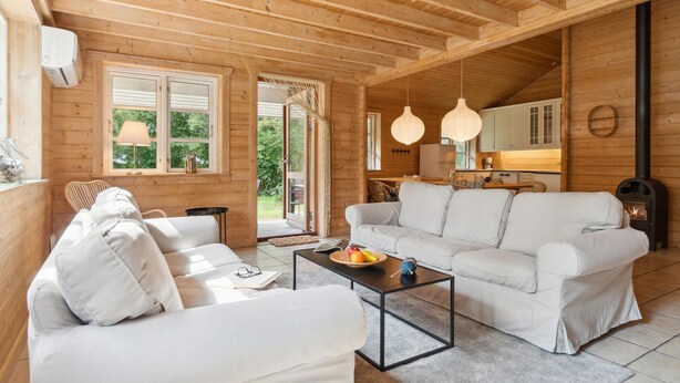Uma cabana de madeira aconchegante com uma sala de estar, incluindo um sofá, uma mesa de centro e um espaço de jantar com mesa e cadeiras.