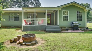 A small, single-story house with a porch, a fire pit, and a grill in the yard. - Guntersville Lake House: Boat Ramp Access! (Scottsboro)
