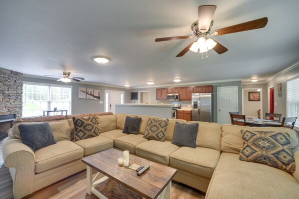 A modern living room with a beige sectional sofa, a wooden coffee table, and a ceiling fan. - Guntersville Lake House: Boat Ramp Access! (Scottsboro)