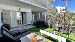 A two-story building with balconies, a patio with outdoor furniture, and a table set with fruits and drinks. - Albufeira Stylish BY Homing (Albufeira)