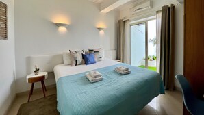 A hotel room with a large bed, two wall-mounted lights, a small side table, and a view of the outdoors through a sliding glass door. - Albufeira Stylish BY Homing (Albufeira)