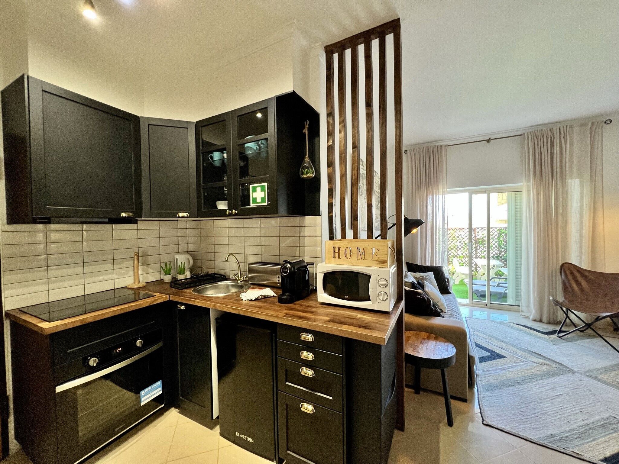 A modern kitchen with dark cabinetry, a built-in microwave, and a wooden island.