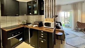A modern kitchen with dark cabinetry, a built-in microwave, and a wooden island. - Albufeira Stylish BY Homing (Albufeira)