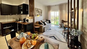 A modern kitchen with dark cabinets, a wooden countertop, and a dining area with a table set for breakfast. - Albufeira Stylish BY Homing (Albufeira)
