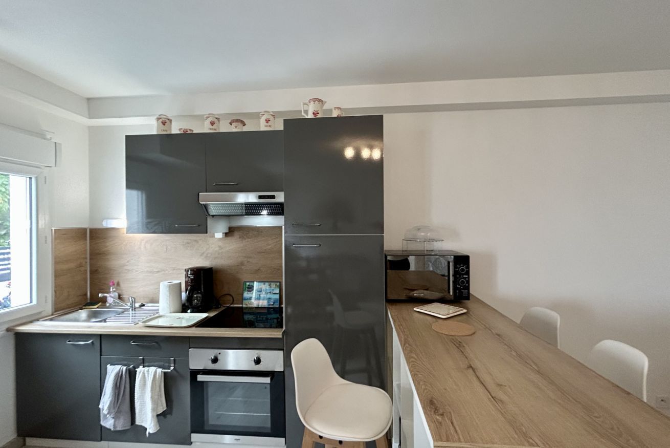 A compact kitchen with a sink, stove, microwave, and a dining area with a table and chairs.