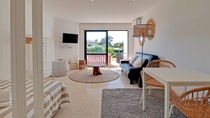 A modern living room with a sofa, a dining table, and a TV mounted on the wall. - Quinta DO Lago Victory Village With Pool (Loulé)