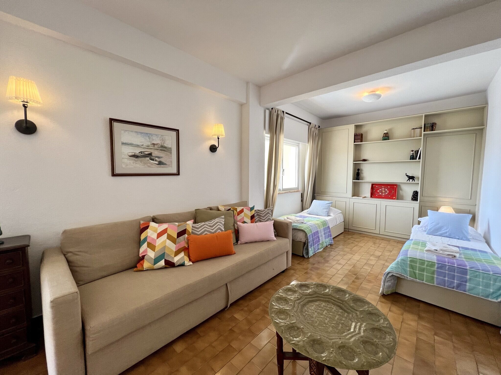Ein gemütliches Zimmer mit einer Couch, einem Bett, einem kleinen Tisch und einem Bücherregal.
