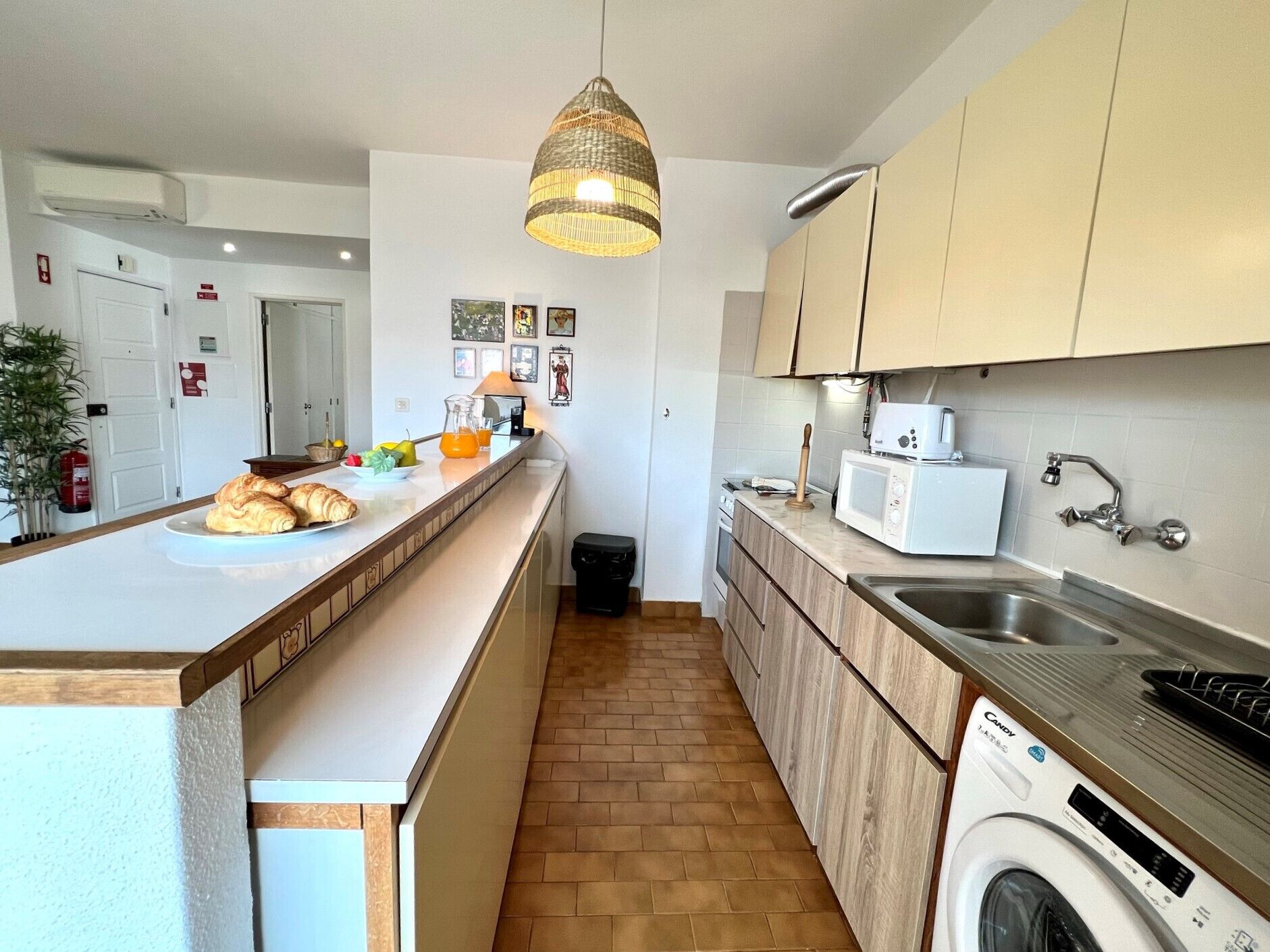 A modern kitchen with a central island, a washing machine, and a microwave.