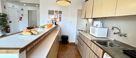 A modern kitchen with a central island, a washing machine, and a microwave.