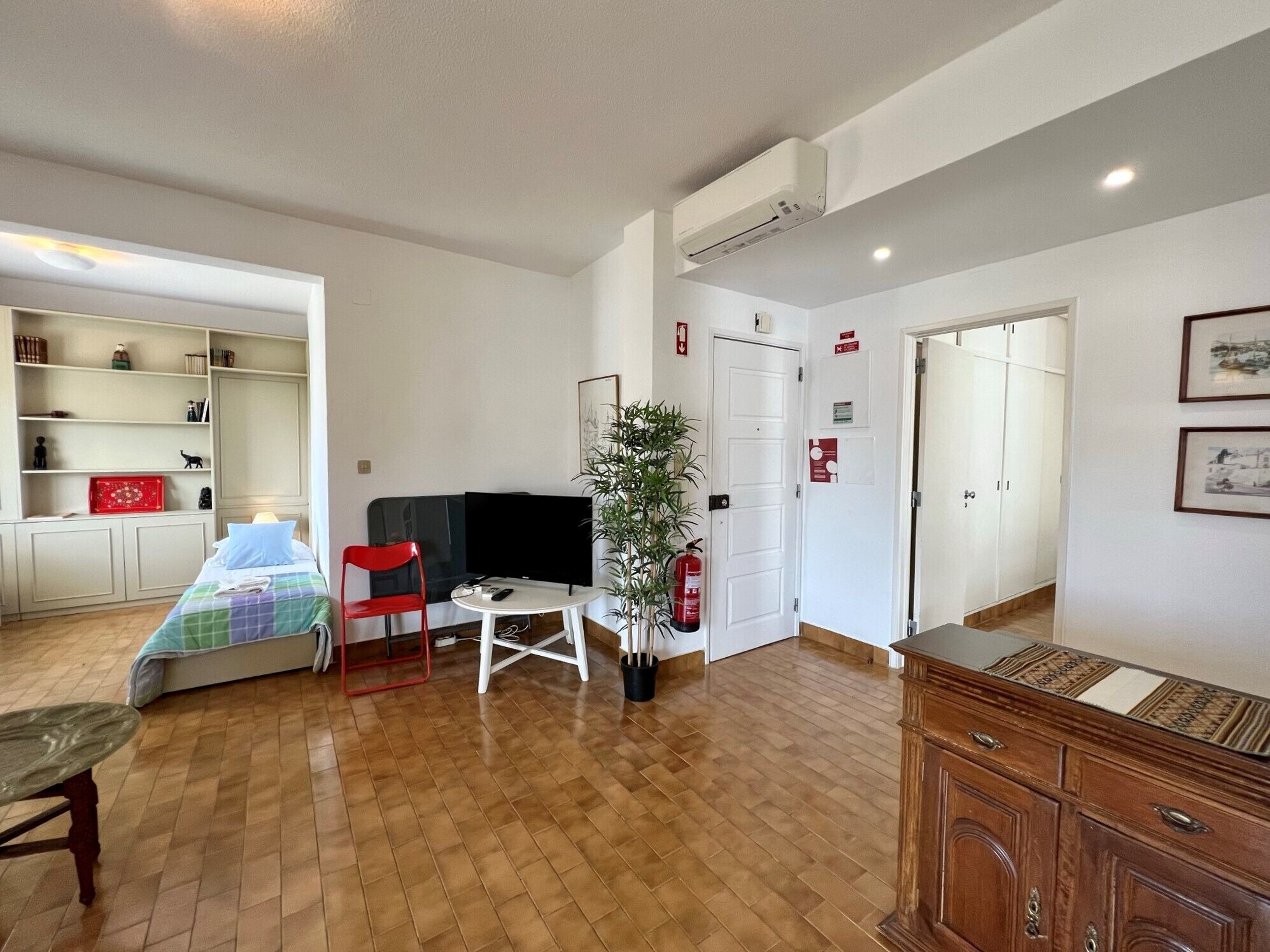 Quarto com cama, escrivaninha, cadeira, planta e guarda-roupa.