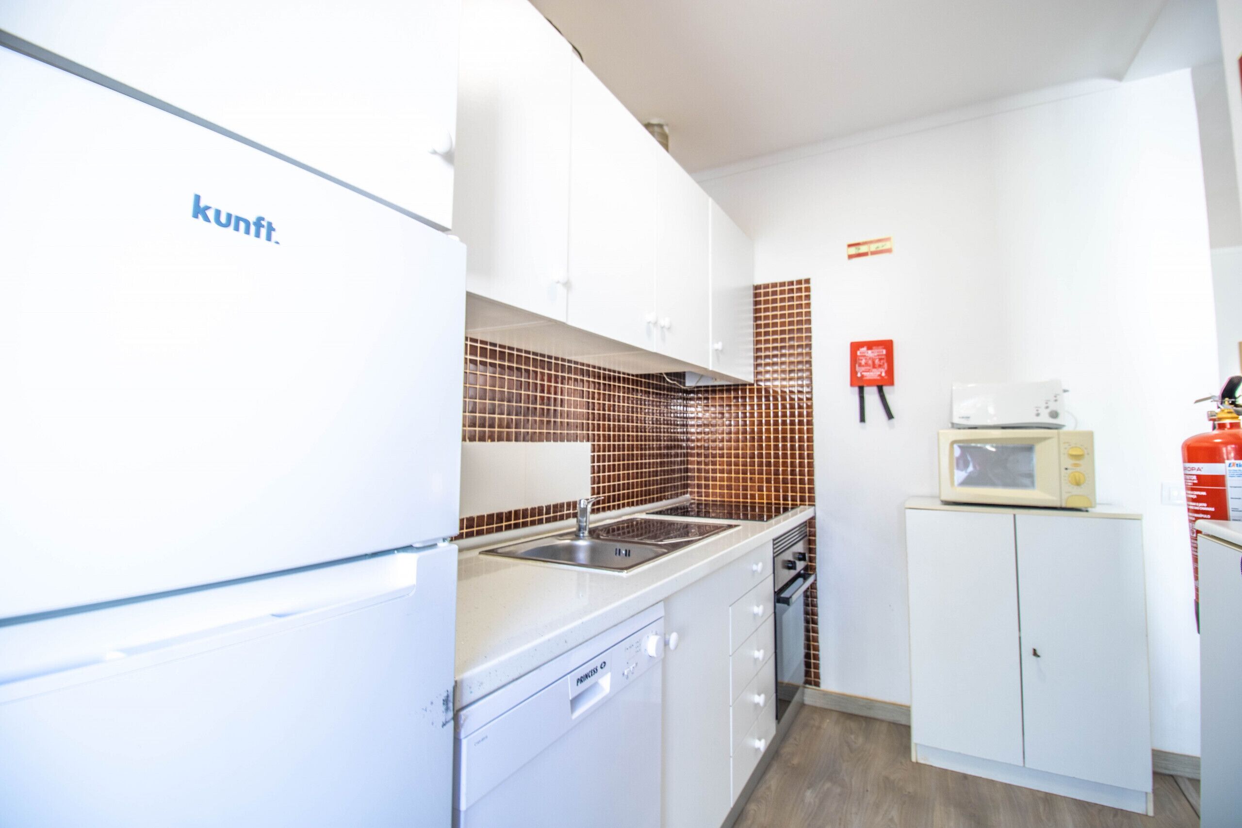 Una cocina moderna con armarios blancos, un microondas y salpicadero de azulejos.